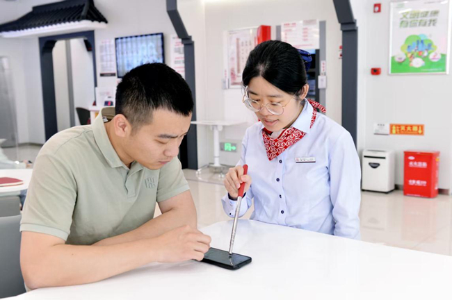 工作人員幫助客戶在手機(jī)上辦理業(yè)務(wù)。工行福州分行供圖