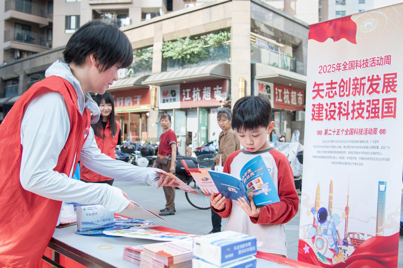 2025年全國(guó)科技活動(dòng)周現(xiàn)場(chǎng)，志愿者向小學(xué)生遞發(fā)水利科普資料。陳美蓉?cái)z