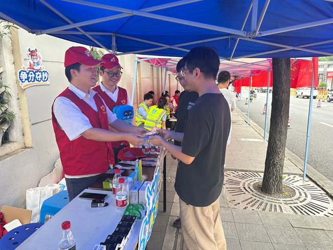 在四川師范大學(xué)附屬中學(xué)的愛心助考點，中建海峽西南公司“蜀光”志愿者們向考生送上應(yīng)急文具