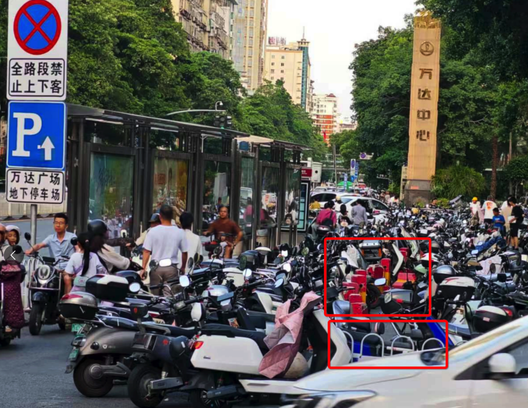 浦西公交站背后路段設(shè)置了非機動車停車區(qū)域，但仍有大量電動車直接停放在白色護欄和紅色隔離墩（紅框位置）外的非機動車道上。李先生攝于7月2日